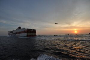 nave barche e elicottero in volo al tramonto