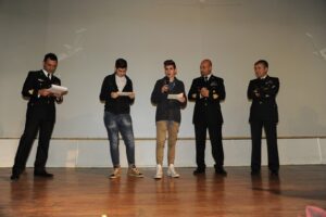 ragazzo dice qualcosa al microfono, accanto a lui personale AM