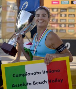 La sportiva menegatti regge in mano la coppa e il cartellone di Campionato Italiano Assoluto Beach Volley