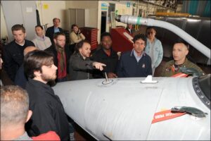 persone guardano aeromobile durante visita hangar