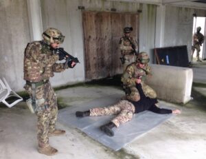 militari in mimetica dentro container, uno a terra, uno lo tiene, altre 3 più distanti puntano le armi